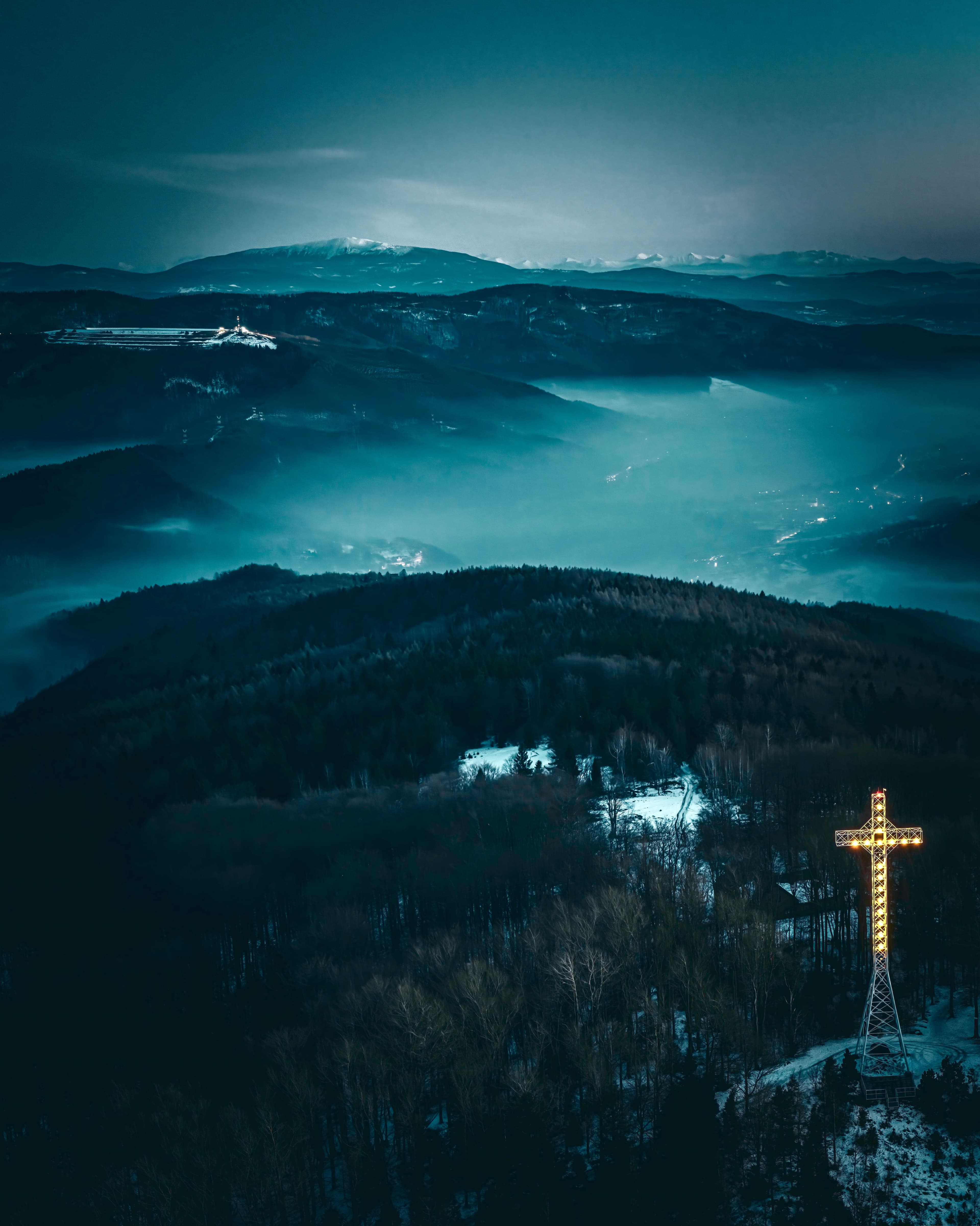 Zdjęcie z drona nocą: oświetlony krzyż na Hrobaczej Łące z widokiem na Górę Żar, Babią Górę i Tatry